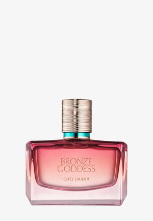 Glazen parfumfles met een gradient roze kleur en een geribbelde gouden dop, gelabeld "BRONZE GODDESS" van Estée Lauder.