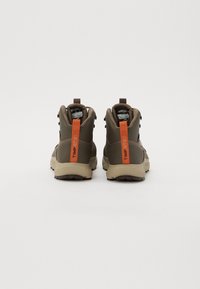 Brune tursko med høy design, med oransje trekkminer, snøresystem og teksturerte gummisåler.
