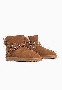 Braune Wildleder-Ankleboots mit weichem Innenfutter, ausgestattet mit einem gewickelten Riemen, der mit silbernen Nieten verziert ist, und einer flachen Gummisohle.