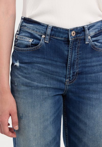Jeans de mezclilla azul con un acabado desgastado, ligero desgaste, diseño de cinco bolsillos y cierre de botón. La tela tiene una textura suave.