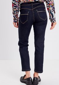 Navyblauwe denim jeans met een slim fit en enkel lengte. Voorzien van twee achterzakken met contrasterende stiksel en een gladde afwerking.