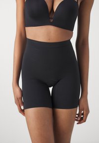 Black high-waisted shaping shorts with a smooth texture and short leg length. Features a seamless design and elastic waistband for comfort.