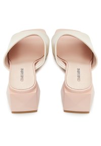 Sandali a infradito con tomaia in pelle crema, design open-toe e tacco blocco geometrico rosa. La vista laterale mette in evidenza la forma unica.