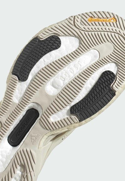 Suela de zapato con una base de goma beige, entresuela blanca texturizada, acentos negros y un logo de Continental. Patrón de surcos en toda la superficie.
