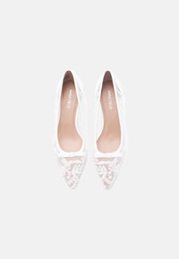 Άσπρα παπούτσια με μυτερή μύτη, επάνω μέρος από δίχτυ με διακόσμηση λουλουδιών με χάντρες και κεντήματα, μαλακή μπεζ επένδυση και κομψό, λιτό σχέδιο.