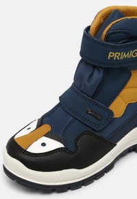 Baskets montantes pour enfants en bleu marine et jaune moutarde, avec des accents noirs et blancs, des bandes Velcro, et des motifs d'yeux ludiques sur l'avant.