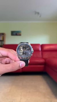 Orologio analogico argento con quadrante grigio, cinturino in pelle, retro trasparente che mostra il movimento e tre sottodial per le funzioni.
