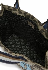 Stofftasche mit Tiermusterakzenten und blauen Akzenten. Das Innere ist mit schwarzem Futter und einem sich wiederholenden, hellgrauen Textmuster gestaltet. Geräumiges Design.