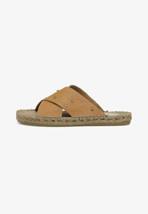 Pruunid nahast slaid sandaalid ristsõlmega rihmadega, kaunistatud hõbedaste nööpidega, ja kootud jute talla korraliku tekstuuri ja mugavuse tagamiseks.