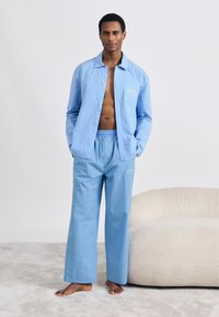 Σετ πιτζάμες με μπλε ρίγες που αποτελείται από πουκάμισο με κουμπιά και τσέπη στο στήθος, καθώς και παντελόνια με ελαστική μέση. Μαλακό, ελαφρύ ύφασμα.