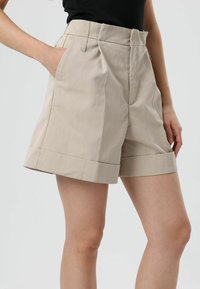 Beige short met hoge taille gemaakt van glad katoen, met zijzakken, opgerolde boorden en een getailleerd silhouet.