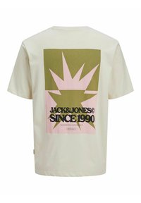 Krémové tričko s krátkým rukávem, které má velký grafický potisk v zelených a růžových barvách, text "JACK & JONES" a design ve tvaru slunečního paprsku.