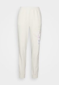 Krémové teplákové kalhoty z měkké tkaniny, s elastickým pasem a manžetami, s multikolorním grafickým designem na boku.