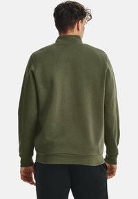 Sudadera verde oliva con cuello alto, puños y dobladillo acanalados. Tejido suave con textura lisa, con un corte relajado y sin marca visible.