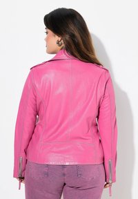 Rosa Lederbikerjacke mit taillierter Passform, Reißverschlusssäumen und Schulterklappen, von hinten gezeigt. Glatte Textur mit glanzvollem Finish.