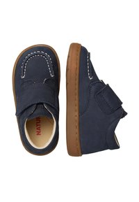 Chaussures en daim bleu marine avec une sangle velcro, semelle en caoutchouc beige clair, coutures blanches contrastantes, bout rond et doublure douce.