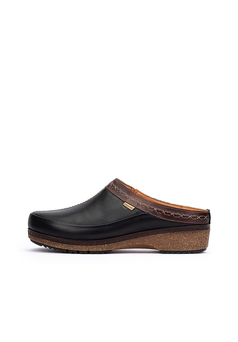 Sabots à enfiler avec une tige en cuir noir, des coutures marron contrastantes et une semelle en liège texturée pour l'adhérence.