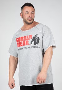 Grijze oversized t-shirt met een verwassen halslijn, voorzien van een zwart-rode grafische print van een gorilla met de tekst "Gorilla Near, Verenigde Staten van Amerika."
