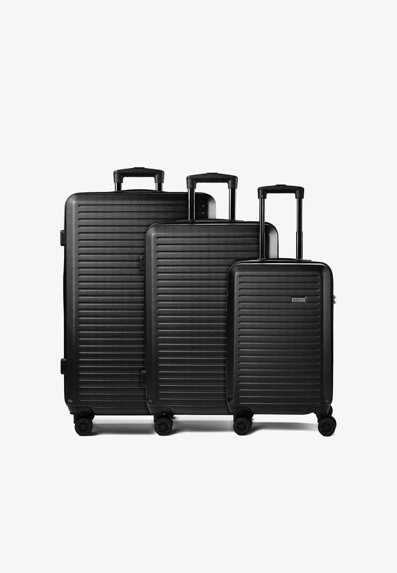 Trois valises rigides noires de tailles différentes avec des rainures horizontales, des poignées télescopiques rétractables et quatre roues pivotantes chacune.