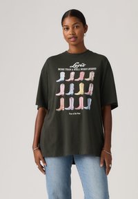 Σκούρο πράσινο υπερμεγέθες t-shirt με πολύχρωφα γραφικά από μποτάκια καουμπόι και το κείμενο «Levi's». Κοντά μανίκια, στρογγυλή λαιμόκοψη, άνετη εφαρμογή.
