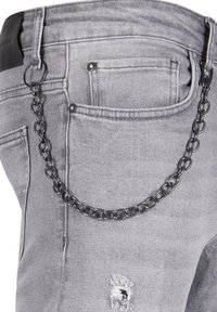 Szare dżinsy denimowe z postarzanym wzorem, z czarnym metalowym łańcuchem przymocowanym do pętelki na pasek dla dodatkowego efektu.