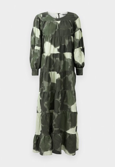 Pitkä, kerroksellinen mekko vihreässä ja beigesä camokuvioinnissa, jossa on pitkät hihat, pyöreä pääntie ja keräilydetailit vyötäröllä.