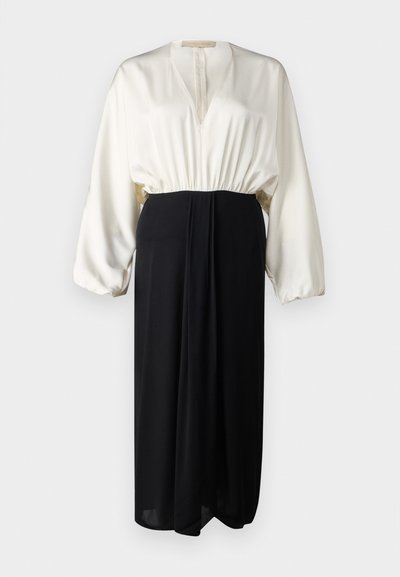Robe à manches longues avec un haut en satin blanc et une jupe noire. La taille élastique et la silhouette fluide créent un effet bicolore.