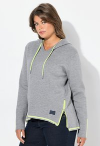 Haut à capuche gris avec un col en V, cordons de serrage et accents d'ourlet en néon vert contrastant, présentant une fermeture éclair sur le côté et une coupe décontractée. Texture de tissu douce.