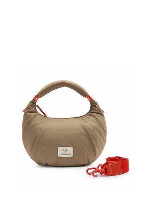 Sac à main beige en forme de croissant avec une poignée rembourrée, des accents de fermeture éclair rouges, une bandoulière rouge amovible et une écusson logo à l'avant.