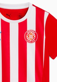 Rot-weißer, vertikal gestreifter Trikot mit Rundhalsausschnitt, das ein rundes Vereinslogo auf der Brust und eine für den Sport geeignete Stoffstruktur aufweist.