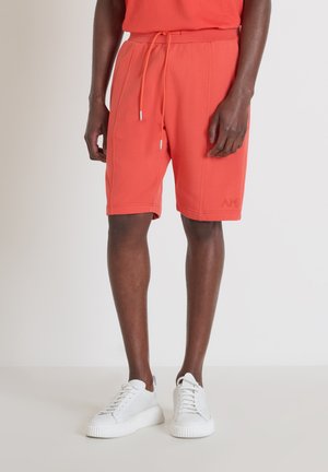 Pantalones cortos de algodón rojos con cinturilla elástica y detalle de cordón, que cuentan con bolsillos laterales y un pequeño logotipo bordado en el dobladillo inferior.