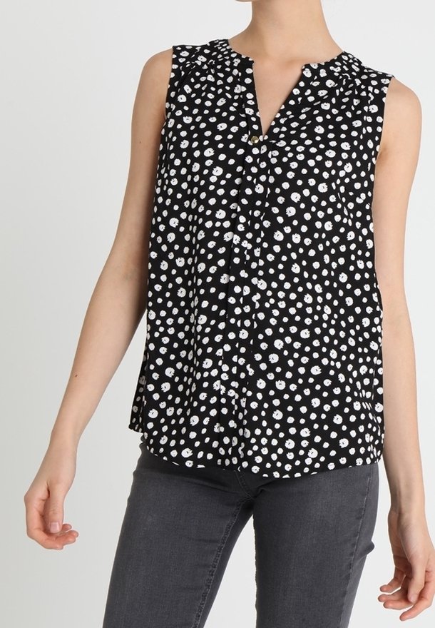 Černá bezrukávová blůza s bílými puntíky, se výstřihem do V a jemnými volány na ramenou. Lehká tkanina s volným střihem.