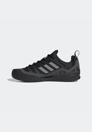 Czarny i ciemnoszary sportowy but Adidas z niskim krojem, trzema szarymi paskami po boku, sznurowaniem i pętlą na pięcie.