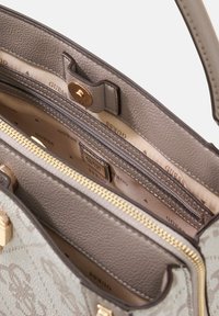 Wnętrze szarej syntetycznej torebki z kieszenią na zamek, gładką fakturą, wytłoczonym logo oraz wzorzystą podszewką z nazwą marki.