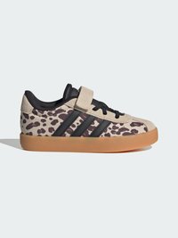 Χαμηλό sneaker με μπεζ και σκούρο καφέ λεοπάρ σχέδιο, μαύρες ρίγες, μπεζ σουέντ λουράκι, μαύρα κορδόνια και φούμα σόλα σε ανοιχτό φόντο.