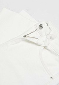 Short en denim blanc avec une fermeture éclair avant partiellement ouverte, bouton métallique et bords bruts.