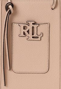 Bežinė odinė kuprinė su tekstūruota apdaila ir ryškiu RL logotipu tamsiame metalikų. Yra kišenė su siūlėmis.