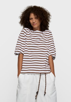 Brązowo-biały, pasiasty top z krótkim rękawem, zaokrąglonym dekoltem i luźnym krojem, zestawiony z białymi spodenkami z detalami sznurka.