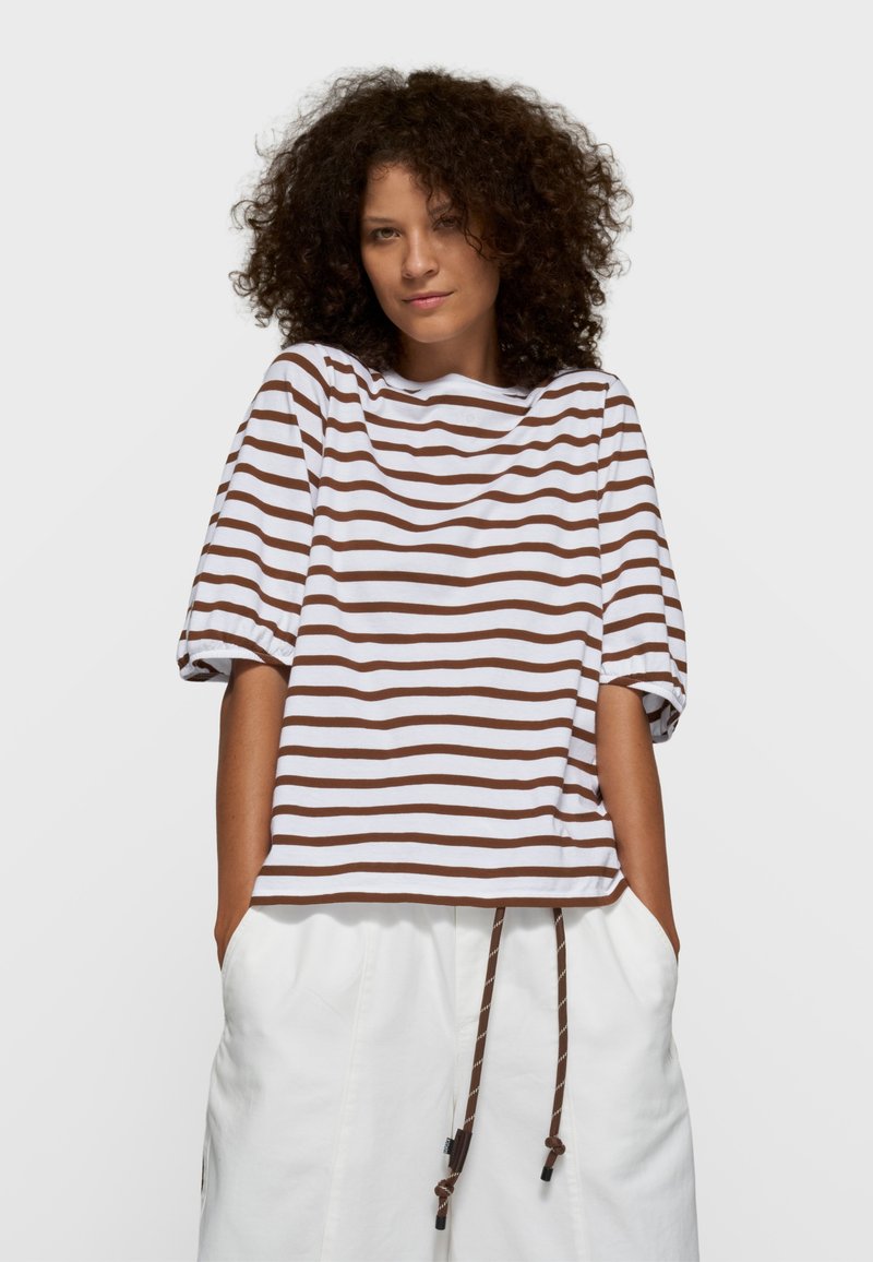 Haut à manches courtes rayé marron et blanc avec un col rond et une coupe décontractée, assorti à un bas blanc avec des détails à cordon de serrage.