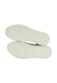 Suole di scarpe in gomma bianca con grip a motivo e marchio testuale, curve ai bordi, caratterizzate da una superficie liscia e texture senza marchi visibili.