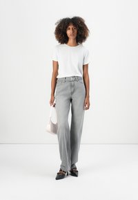 Grå høytlivsjeans, hvit t-skjorte med korte ermer, svarte spisse sko og en lys rosa veske. Glatt stoff, avslappet passform og klassisk design.