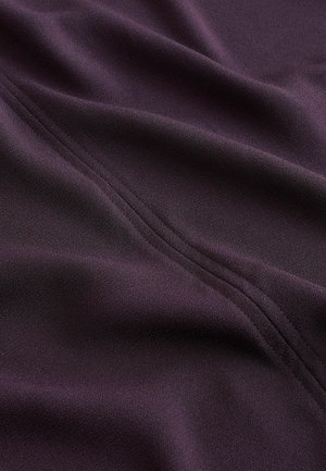Lila Stoff mit weicher Textur, einem dezenten Glanz und sichtbarer Naht entlang einer Seite, entworfen für Vielseitigkeit.