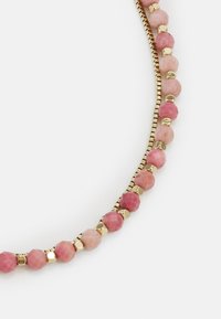 Beaded necklace with pink and peach faceted stones, interspersed with gold-colored metal accents, featuring a curved design and smooth texture.