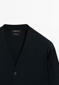 Svart bomullskofta med V-ringning, ribbad textur och en enda knappslutning. Etiketten säger "Massimo Dutti," vilket indikerar märke och material.