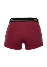 Rote Baumwoll-Boxershorts mit einem schwarzen Elastikbund, versehen mit einem weißen Logo und einem dünnen goldenen Akzent, entworfen für Komfort und Passform.