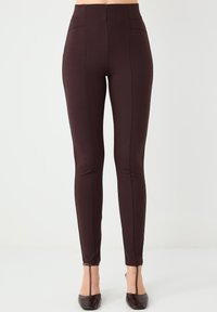 Legginsy z wysokim stanem, dopasowane, w ciemnoczerwonym kolorze z przeszyciami i gładką teksturą. Posiadają zamek błyskawiczny przy kostce oraz minimalną ilość szwów.