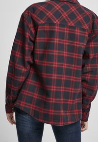 Röd och marinblå rutigt flanellskjorta med lång ärm, knappdetaljer och en något rundad nederkant bak. Mjuk textur, avslappnad passform.