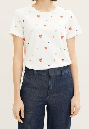 Weißes Baumwoll-T-Shirt mit einem verstreuten Herzmuster in Orange, Lila und Schwarz. Kurze Ärmel und runder Ausschnitt.