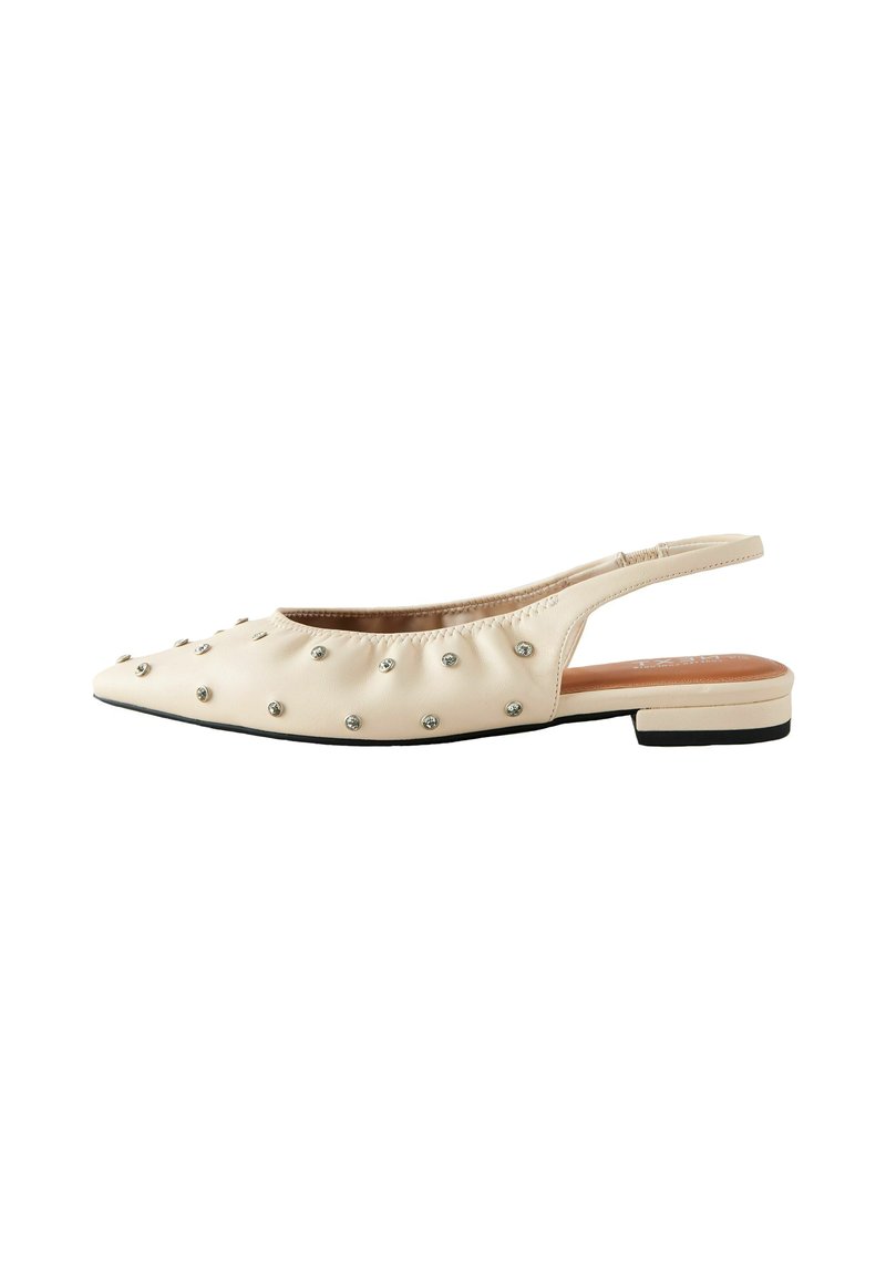 Beige slingback-kenkä, jossa on terävä kärki, rypytetty muotoilu ja hopeiset niitit yläosassa. Litteä pohja ja pieni loiva korko.