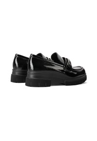 Scarpe platform in pelle verniciata nera con punta arrotondata, prominente dettaglio della cinghia e suola in gomma testurizzata. Finitura lucida con un design elegante.